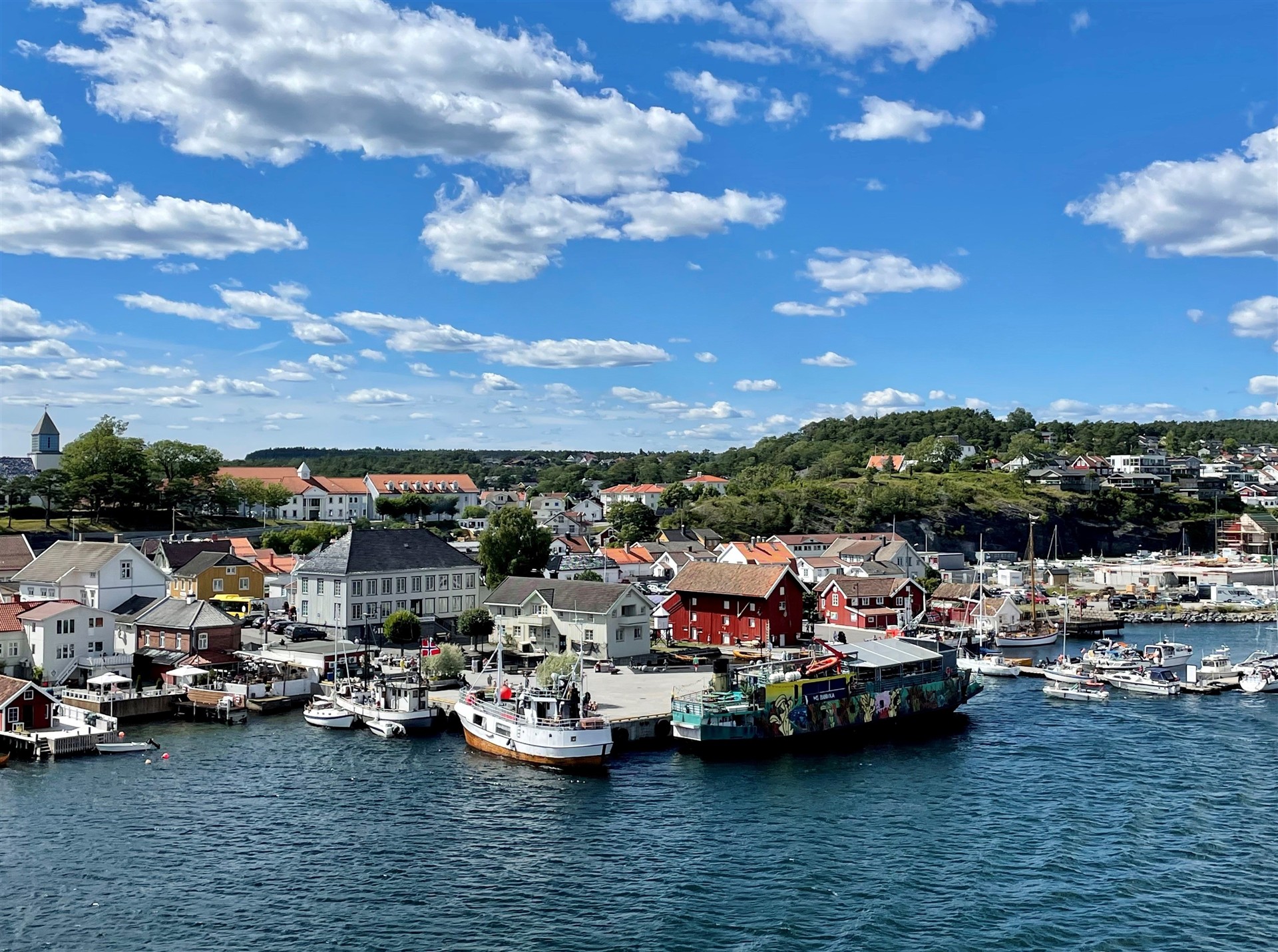 Utsikt over Langesund fra sjøen med båtliv, deler av torget og rådhuset.