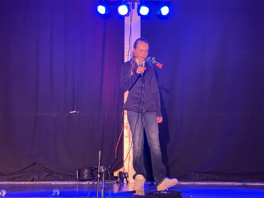 Jente som står på scenen med en rose i munnen - Klikk for stort bilde