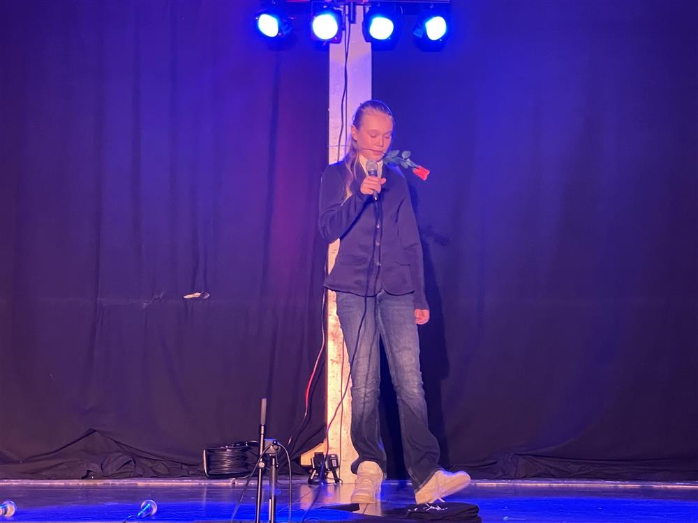 Jente som står på scenen med en rose i munnen - Klikk for stort bilde