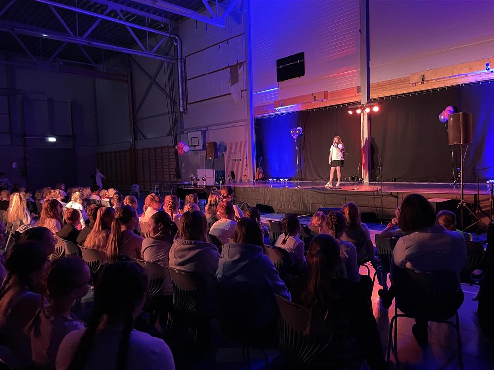 Publikum som ser på en jente som opptrer på scenen - Klikk for stort bilde