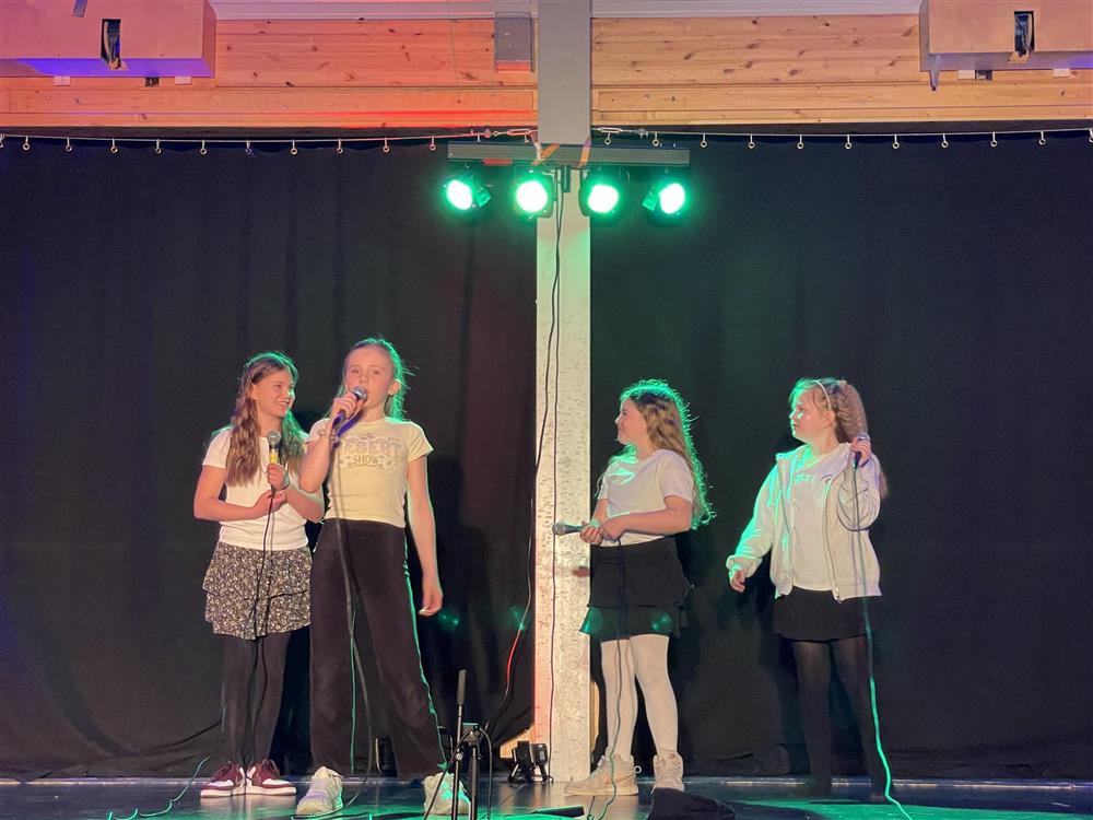 Jenter som smiler og synger på scenen - Klikk for stort bilde